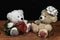 Two cute cuddly teddy bears with single red rose iand white bow on wooden table on dark background