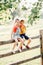 Two cute funny Caucasian children boy girl sitting on wooden rustic fence in park outside. Friends siblings kids hugging