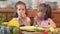 Two cute girls are laughing and eating a juicy yellow mango