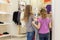 Two cute girls near a mirror try on clothes in a modern store