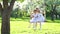 Two cute girls sisters swinging on wooden swing in beautiful spring time park