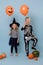 Two cute kids in witch and skeleton costumes holding orange halloween balloons