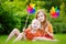 Two cute little girls holding colorful toy pinwheels on sunny summer day