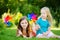 Two cute little girls holding colorful toy pinwheels on warm and summer day