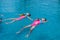 Two cute little girls in life jackets having fun swimming in the pool. Cute sisters practicing floating in the pool. Summer