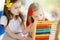 Two cute little girls playing with abacus at home. Big sister teaching her sibling to count.