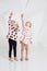 Two cute little girls standing in pink clothes with black hearts on the white wall background in the studio.