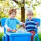 Two cute little kid boys wearing Easter bunny ears, painting colorful eggs and having fun outdoors. Family, siblings