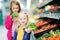 Two cute little sisters choosing broccoli in a food store or a supermarket