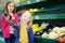 Two cute little sisters choosing eggplants in a food store or a supermarket