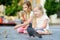 Two cute little sisters feeding birds on summer day. Children feeding pigeons and sparrows outdoors.