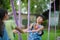 Two cute little sisters having fun playing in the playground during summer. Adorable little girl rocking a horse in a playground