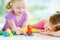 Two cute little sisters having fun together with colorful modeling clay at a daycare