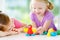 Two cute little sisters having fun together with colorful modeling clay at a daycare. Creative kids molding at home.
