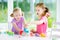 Two cute little sisters having fun together with modeling clay at a daycare. Creative kids molding at home. Children play with pla