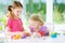 Two cute little sisters having fun together with modeling clay at a daycare. Creative kids molding at home. Children play with pla