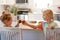 Two cute little sisters having homemade cookies for snack in a light and bright kitchen