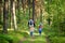 Two cute little sisters hiking in a forest with their grandmother