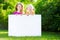 Two cute little sisters holding big blank whiteboard