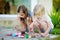 Two cute little sisters painting on stones together