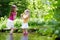 Two cute little sisters playing in a river wearing raining boots