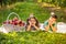 Two cute siblings laying on the carpet in garden, basket full of ripe apples on the side.