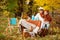 Two cute sisters  on picnic in autumn park. Adorable little girls  having tea party outside in the autumn garden.  Girls drinking