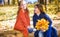 Two cute smiling 8 years old girls chatting in a park on a sunny autumn day.