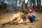 Two cute young girls sitting by a bonfire on cold autumn day. Children having fun at camp fire. Camping with kids in fall forest