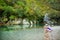 Two cute young sisters having fun by Voidomatis river on warm and sunny summer day during family vacations in Zagoria, Greece