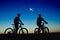 Two cyclists on the background of night sky and moon, watching the plane