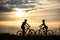 Two cyclists posing with bikes against amazing sky background.