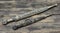 Two daggers with ornate pattern on old wooden background close-up.