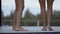 Two dancing slender tanned pairs of female legs. Girls have fun on the lounge near swimming pool one weekend