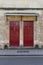 Two dark red front doors on the stone wall