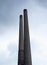 Two dark tall and high smokestacks and cloudy overcast sky