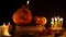 Two decorative pumpkins Jack with smiles standing on old books in candle light