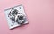 Two delicious fresh hearty black and white donuts lie on a white square plate on a pink background