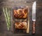 Two delicious grilled piece of pork on a cutting board with a knife for meat and rosemary wooden rustic background top view clo