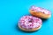 Two delicious lilac donuts with sprinkle on bright blue background