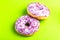 Two delicious lilac donuts with sprinkle on bright green background