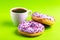 Two delicious lilac donuts with sprinkle and cup of coffee