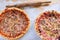 Two delicious pizzas on wooden table scattered with flour