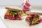 Two delicious vegetable sandwiches on a wooden board. In the background, a jar of sauce. Selective focus