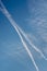 Two diagonal chem trails from airplanes in the blue sky