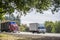 Two different carriers red big rig semi truck with dry van semi trailer and small rig white cab over truck with box trailer