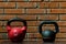 two different dumbbells against the backdrop of a brick wall in the gym