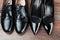 Two different Pairs of black classic modern shoes on the wooden floor background