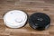 Two different Robotic vacuum cleaners illustrating problem of choosing household helper. modern smart appliance for cleaning house