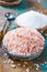 Two different types of natural salt in stone bowls on wooden surface. White sea salt, pink Himalayan salt